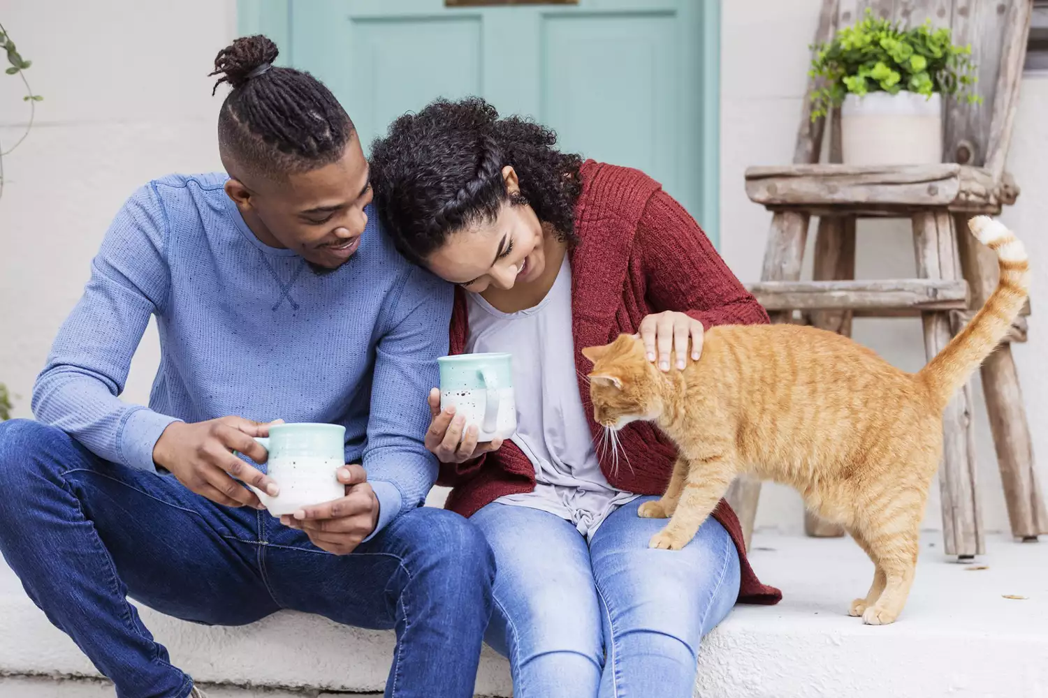 couple sitting on steps talking to their cat; cats react to baby talk from owners