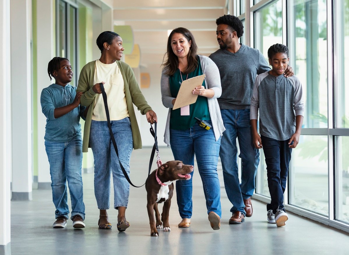 A volunteer at an animal shelter helping an African-American family with two boys adopt a rescue dog.